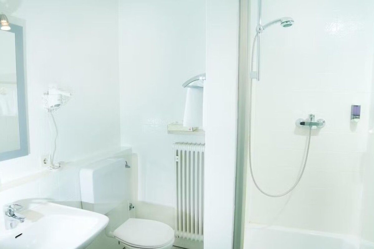 Ein modernes Badezimmer mit einer Duschkabine aus Glas, einem weißen Waschbecken und einer Toilette.