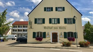Un edificio de dos pisos con un letrero que dice "Gasthof zum Hirsch".