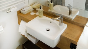 Un baño moderno con tocador de madera, dos lavamanos, un espejo grande y zona de ducha.