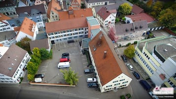 Vista aerea di una città con un edificio centrale dotato di tetto rosso, circondato da diversi altri edifici con tetti di colori differenti.