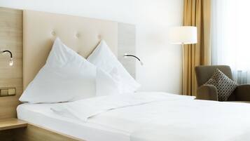 Een hotelkamer met een groot bed, twee kussens, een nachtkastje, een lamp en een stoel.