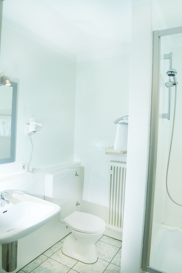 Un baño con lavamanos, inodoro y ducha blancos.