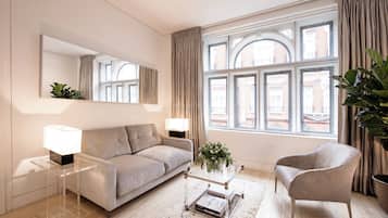 Ein modernes Wohnzimmer mit einer Couch, einem Sessel, einem Couchtisch und einem großen Fenster mit Vorhängen.