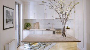A modern kitchen with white cabinets, a marble countertop, and a vase with branches. - No.5 Maddox Street (London)