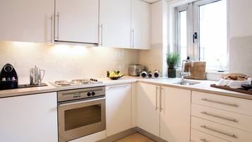 A modern kitchen with white cabinetry, a stainless steel stove, a toaster, and a sink.