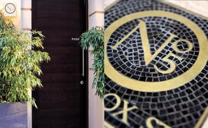 A hotel entrance with a dark wooden door, a 'PUSH' sign, and a mosaic clock with a '5' symbol. - No.5 Maddox Street (London)