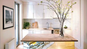 A modern kitchen with white cabinets, a marble countertop, and a vase with branches. - No.5 Maddox Street (London)