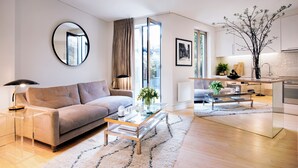 A modern living room with a sofa, coffee table, and a view of the city through large windows. - No.5 Maddox Street (London)