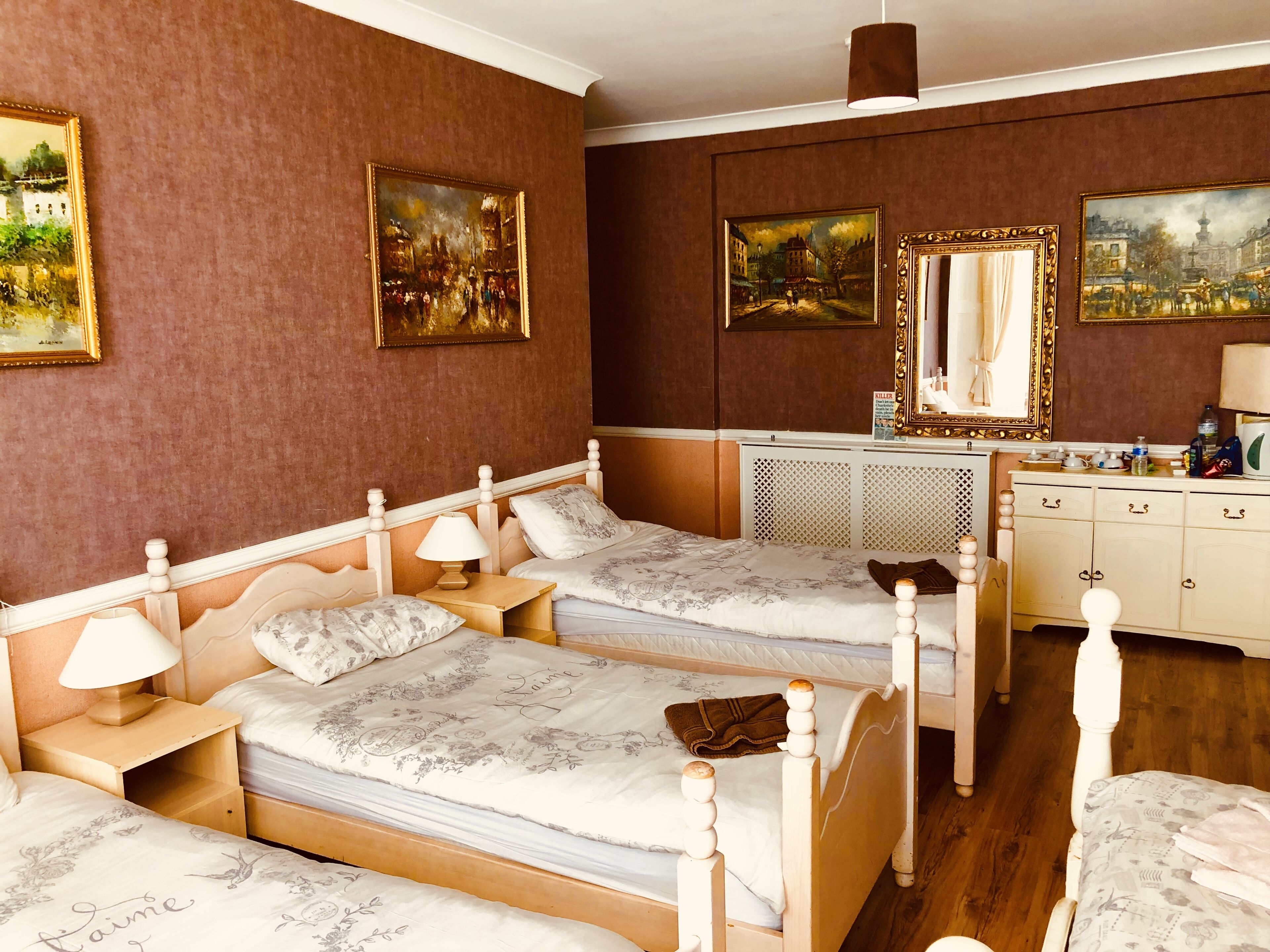 A hotel room with two beds, a dresser, and a mirror.