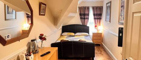 A bedroom with a bed, a dresser, a mirror, a nightstand, and a door.