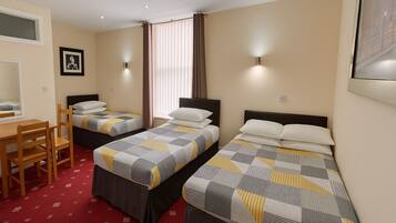 A hotel room with two single beds, a desk, and a chair.