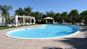 Una piscina con sillas de descanso y un pabellón.