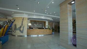 Un moderno vestíbulo de hotel con mostrador de recepción, un mural abstracto grande y una zona de estar curva.