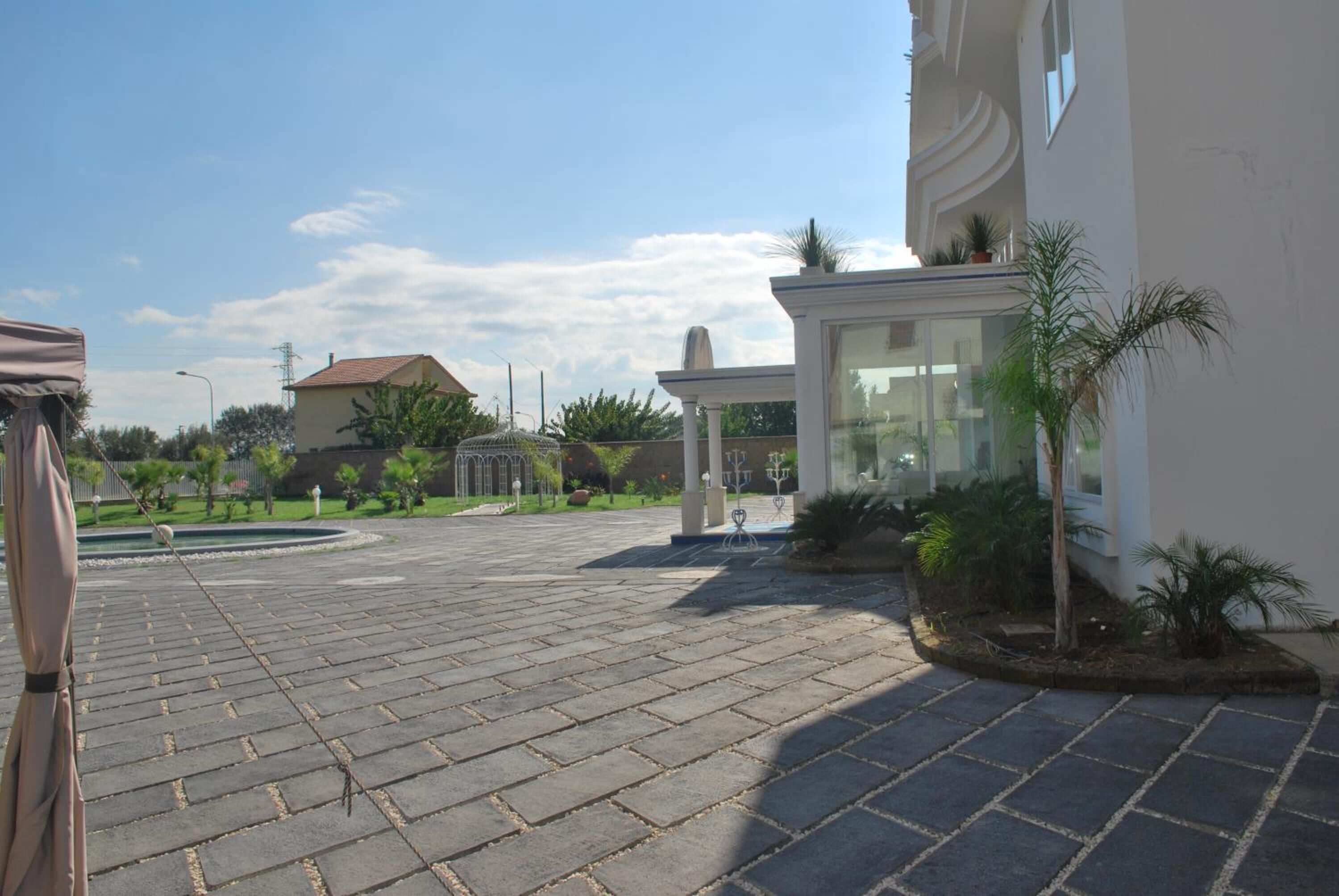 Un patio empedrado con un mirador, palmeras y un edificio con fachada de vidrio.