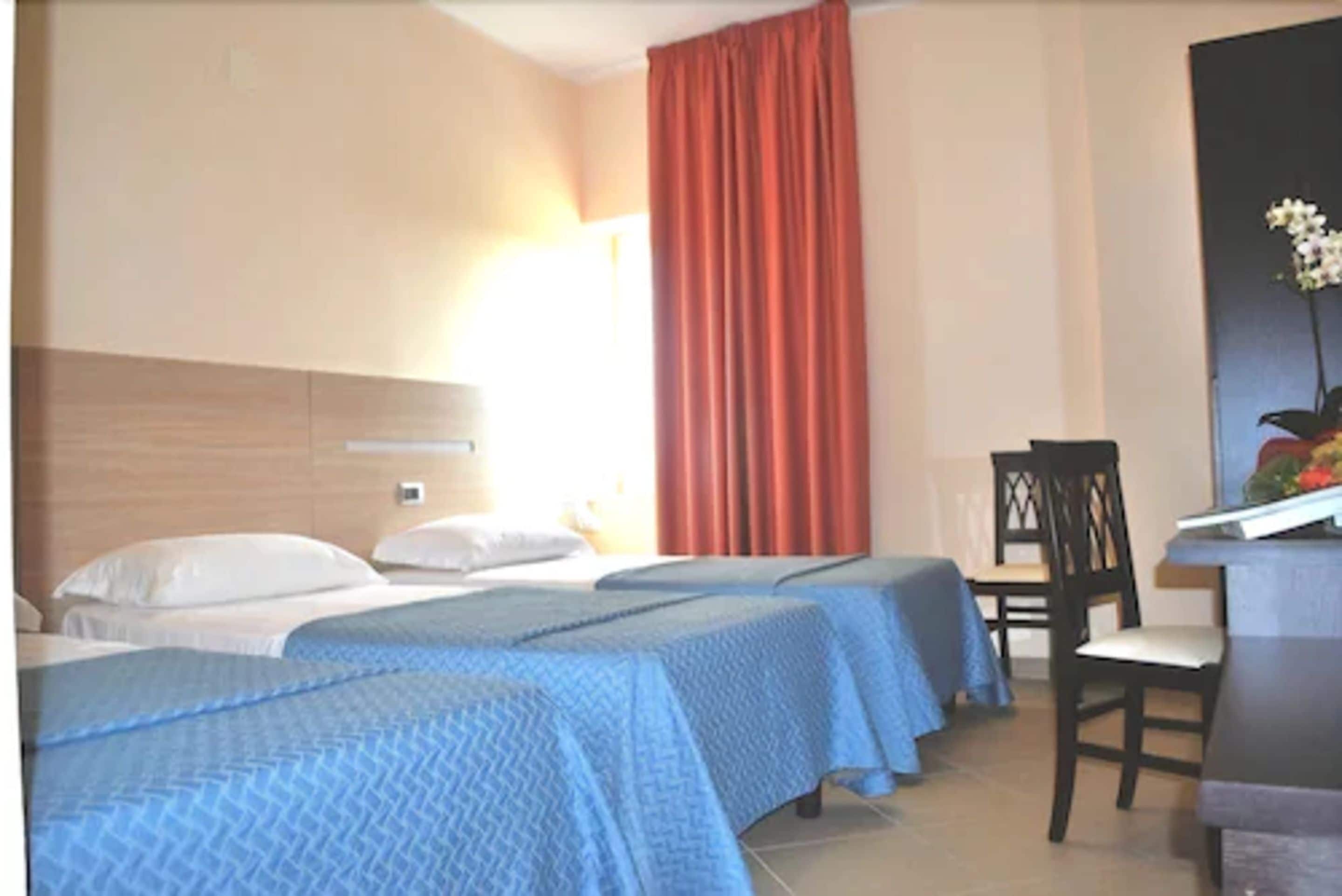 Habitación de hotel con dos camas, un escritorio y una silla.