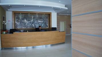 A reception desk with a large abstract painting above it, a receptionist, and a modern interior design.