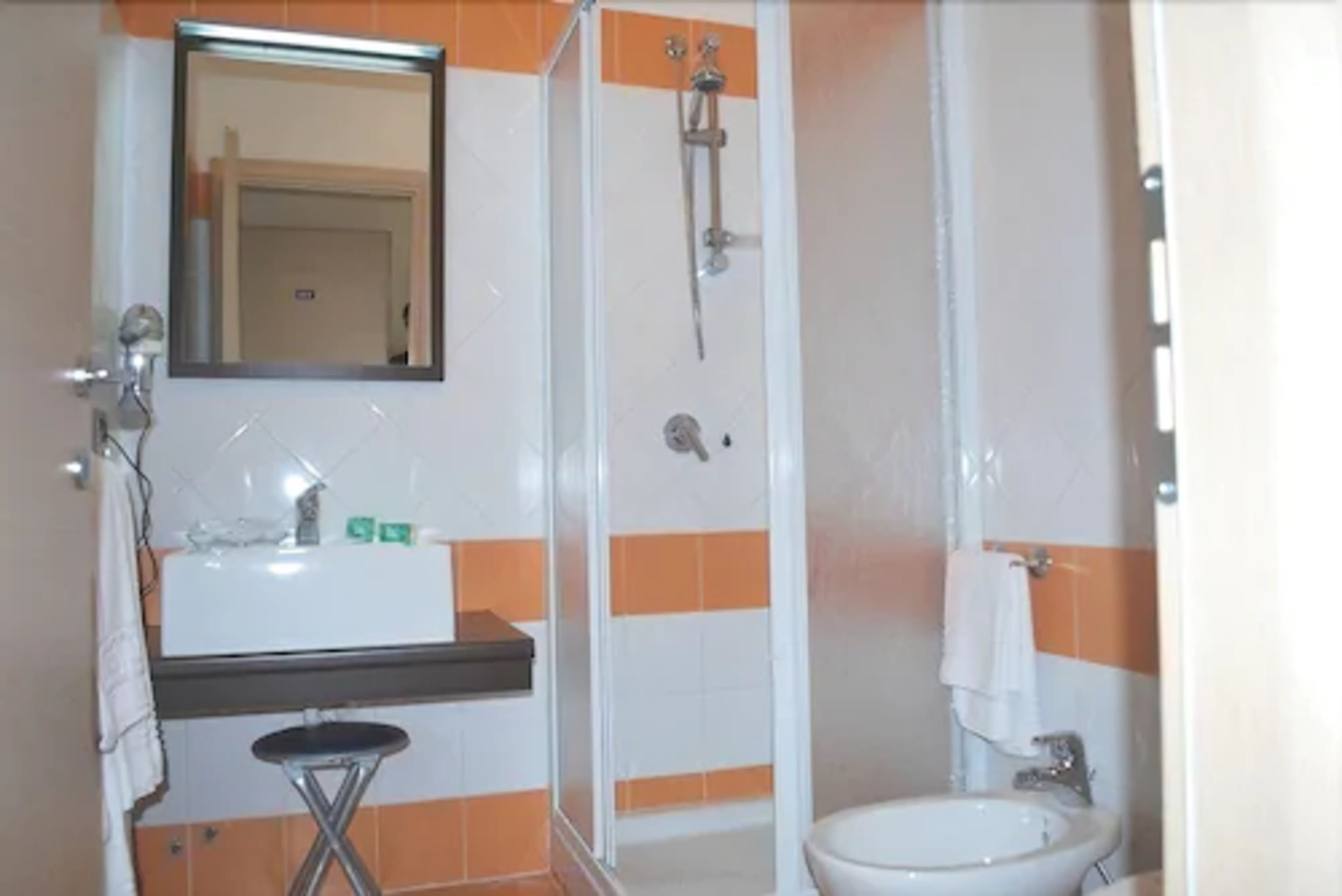 Een badkamer met een wastafel, spiegel en douche.