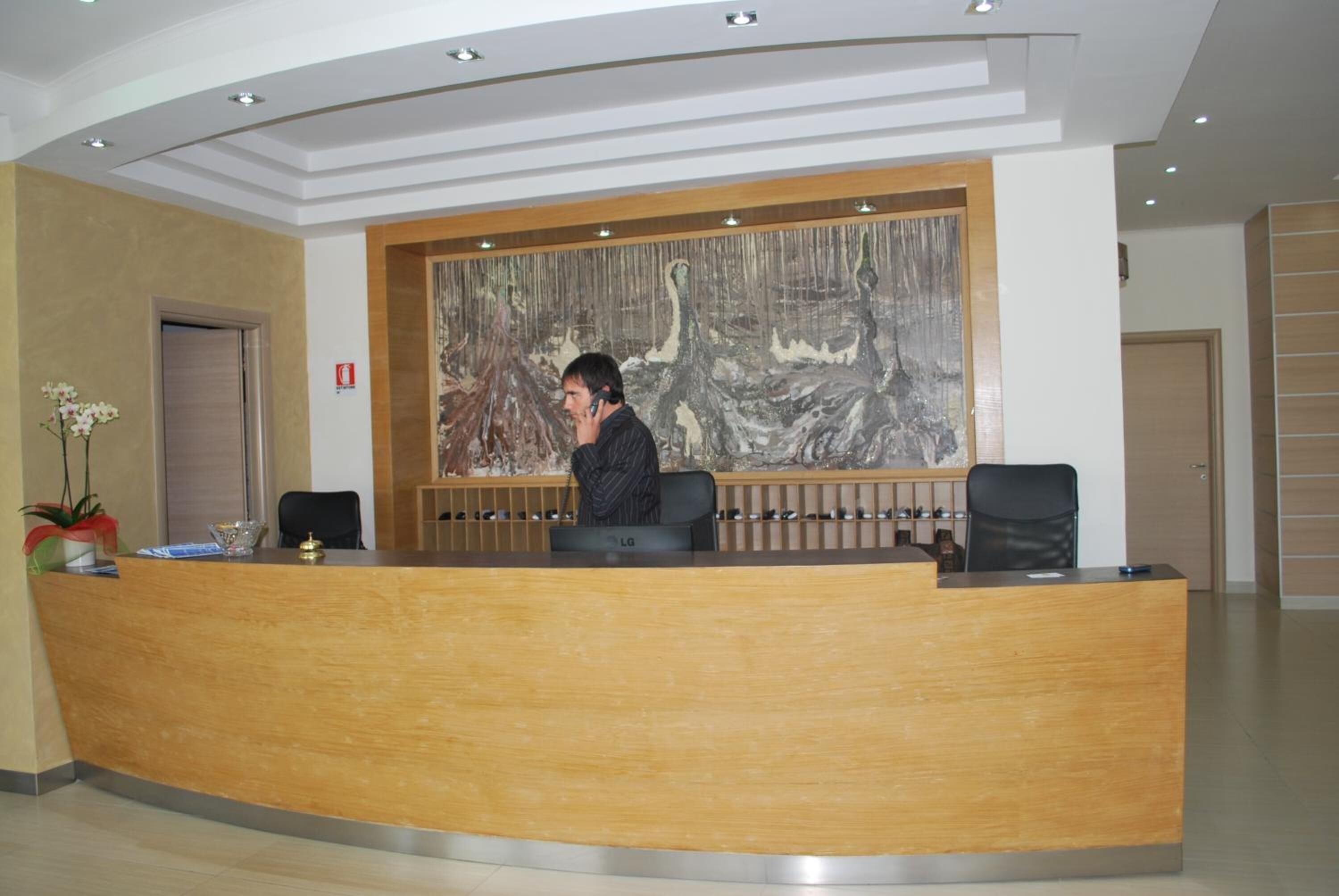 Un comptoir d’accueil orné d’un grand tableau abstrait au mur, agrémenté d’une plante en pot et doté d’un aménagement intérieur moderne.
