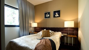 A neatly made bed with a patterned blanket, two pillows, and a bedside table with a lamp. There are two framed pictures on the wall. - King George 83 Vacation apartments (Tel Aviv)