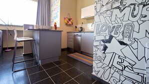 A compact kitchen with a bar stool, a small island, and a colorful rug. - King George 83 Vacation apartments (Tel Aviv)