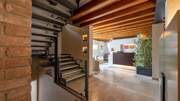Un interior moderno con una escalera, vigas de madera en el techo y una zona de cocina al fondo.