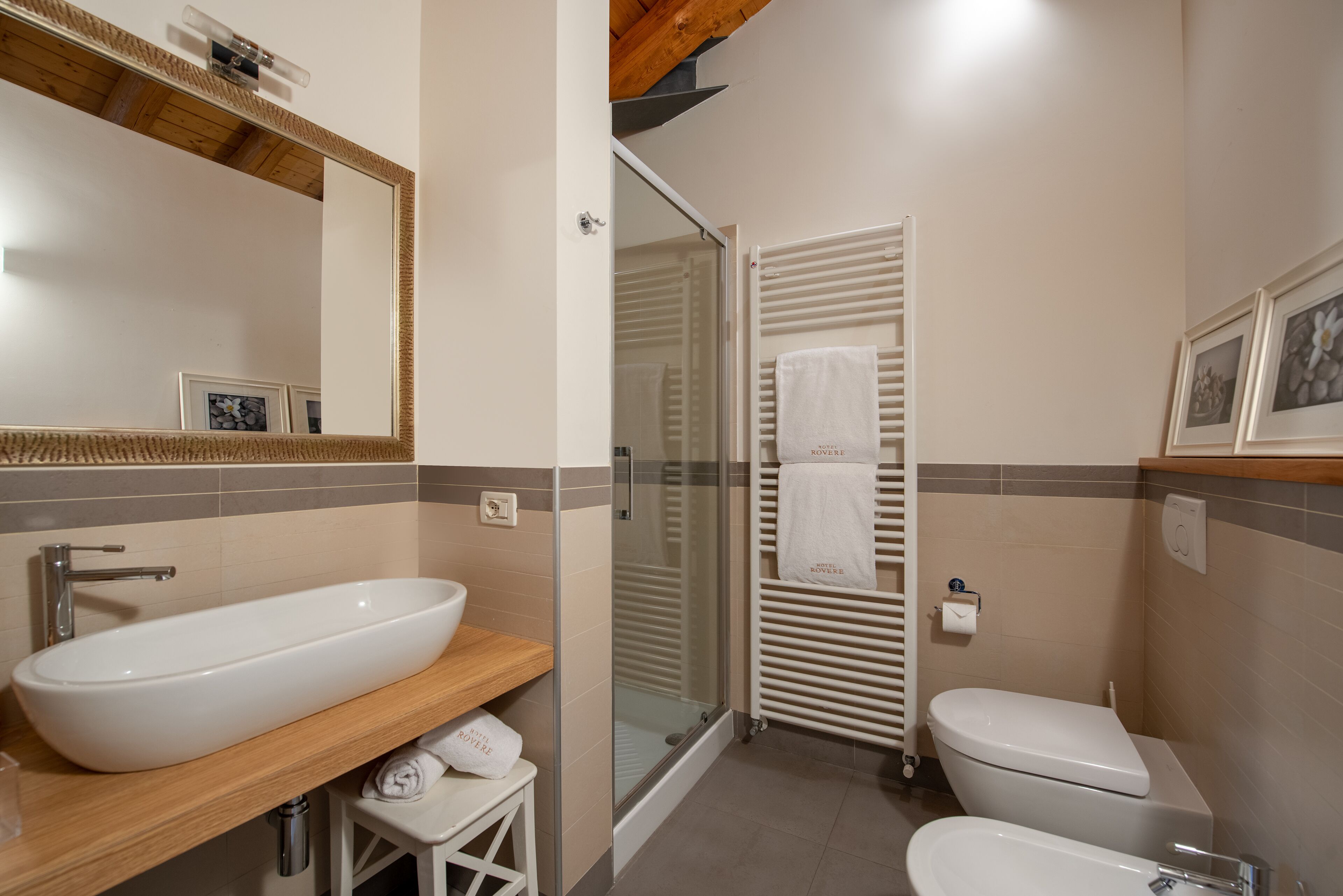 Een moderne badkamer met een groot ovaal wastafel, toilet en een douchecabine met glazen wanden.
