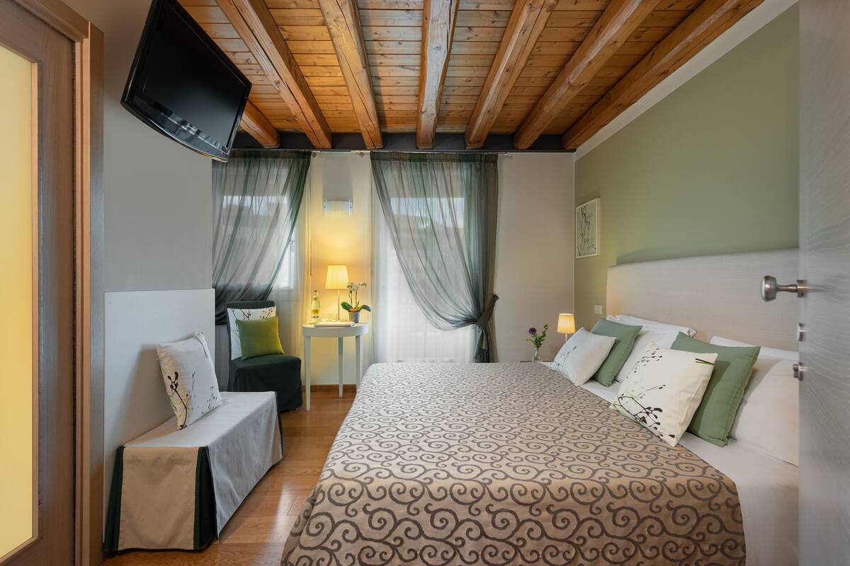 A bedroom with a bed, bedside tables, a TV, and curtains.