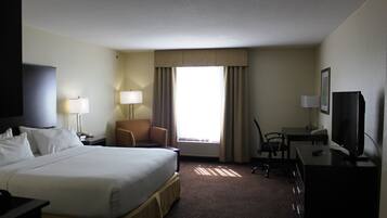 A hotel room with a large bed, a desk with a computer, a chair, and a television.