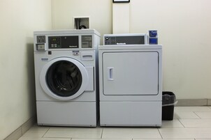 A front-loading washer and dryer unit with a digital display, control panel, and a notice label.