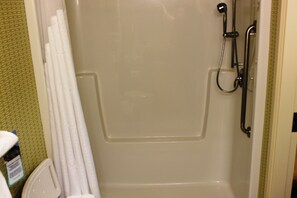 Une cabine de douche dotée d’une porte en verre, d’un pommeau de douche à main et d’un autre pommeau de douche fixé au mur.