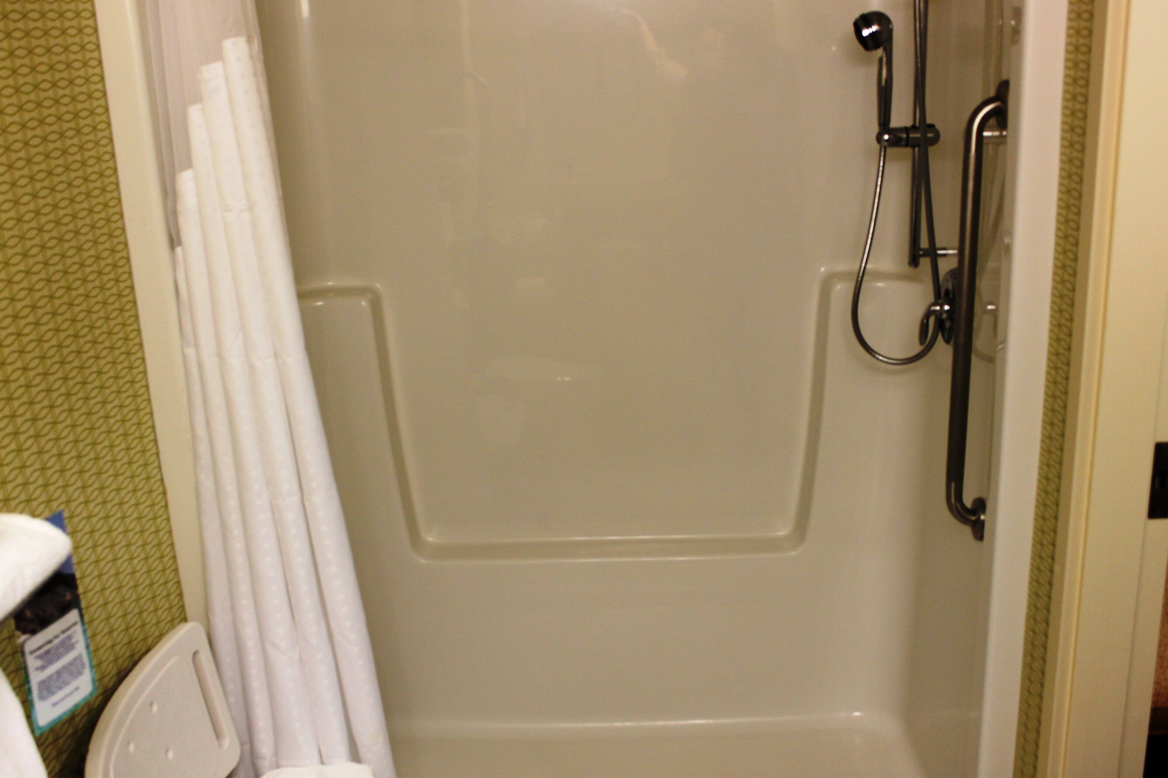 A shower with a handheld showerhead, a handheld showerhead, and a shower control panel.