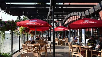 Un espace extérieur aménagé avec des parasols rouges, des tables et des chaises en bois.