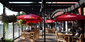 An outdoor seating area with red umbrellas, wooden tables, and chairs. - Holiday Inn Express Yorkton East by IHG (Yorkton)