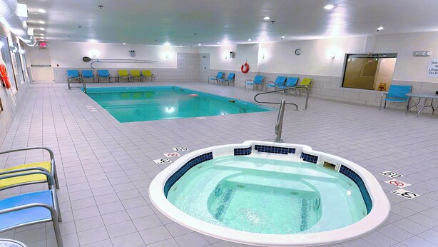 Een zwembadgedeelte met twee zwembaden, een jacuzzi en ligbedden.