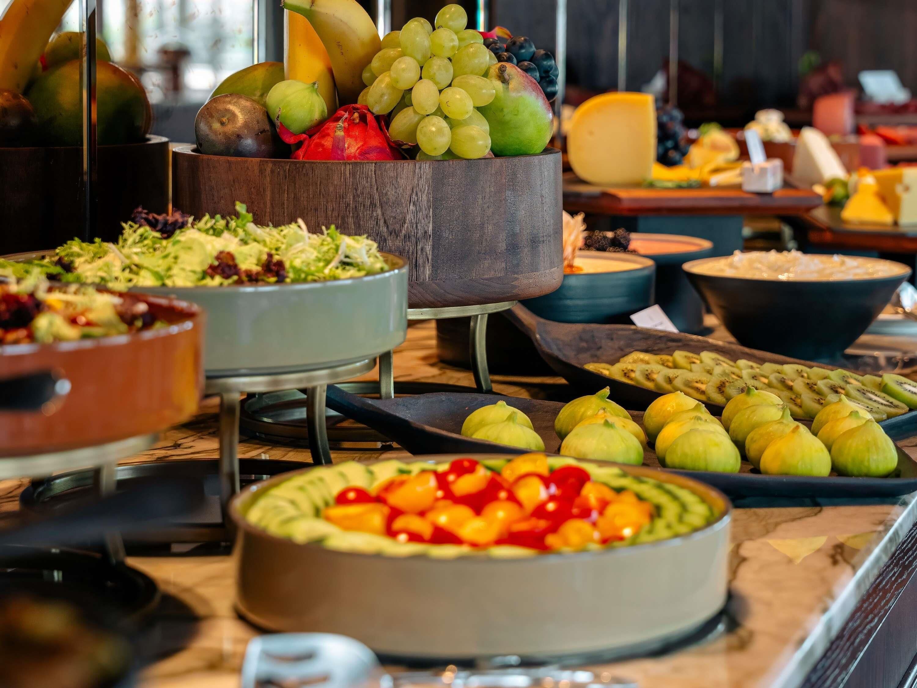 A buffet with various food items including fruits, salads, and cheese.