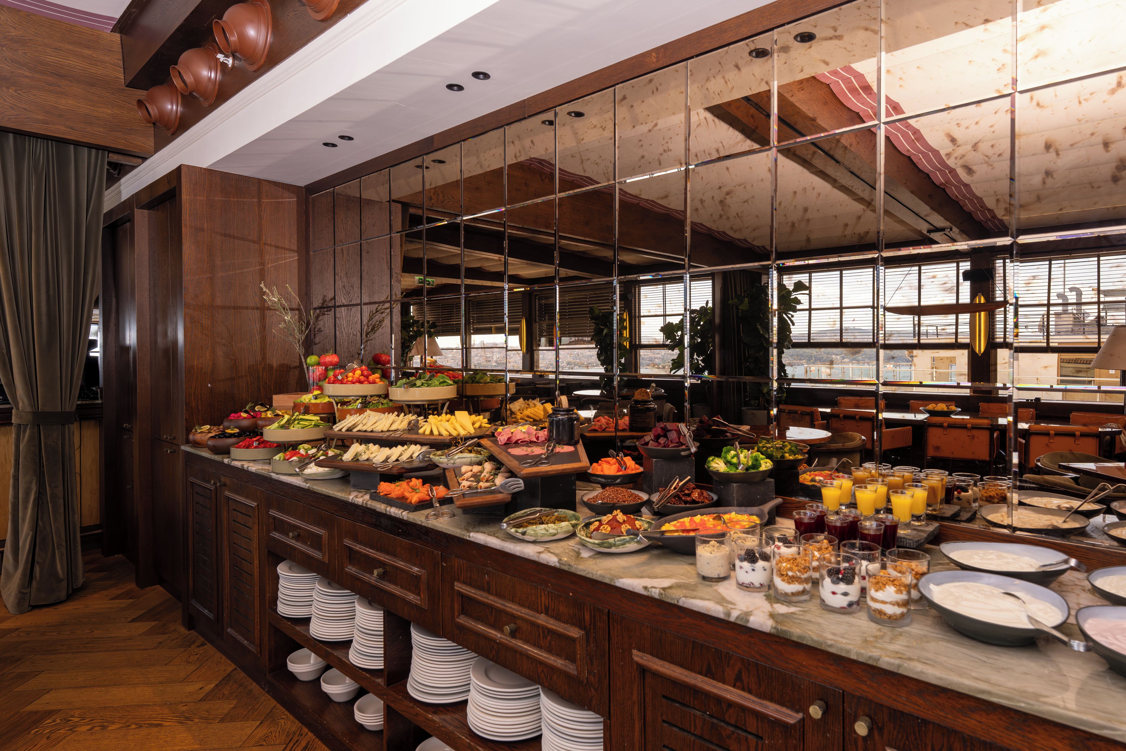 A buffet with a variety of food options and a large mirror reflecting the room.