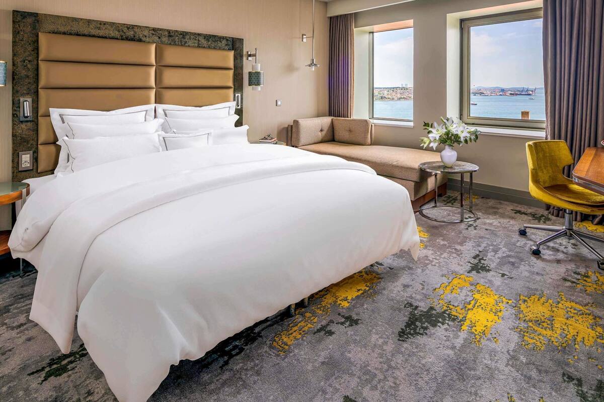 Hotelkamer met een groot bed, een sofa, een kleine tafel, een stoel en uitzicht op de stad.