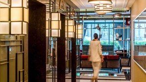 A modern lobby with marble floors, a central seating area, and a view of the street outside.