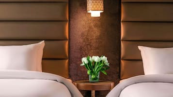 Habitación de hotel con dos camas, un adornado panel decorativo y una pequeña mesa con un florero.