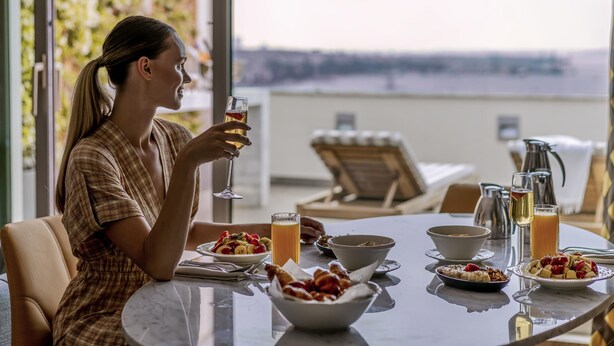 A dining table with breakfast items and a glass of orange juice.
