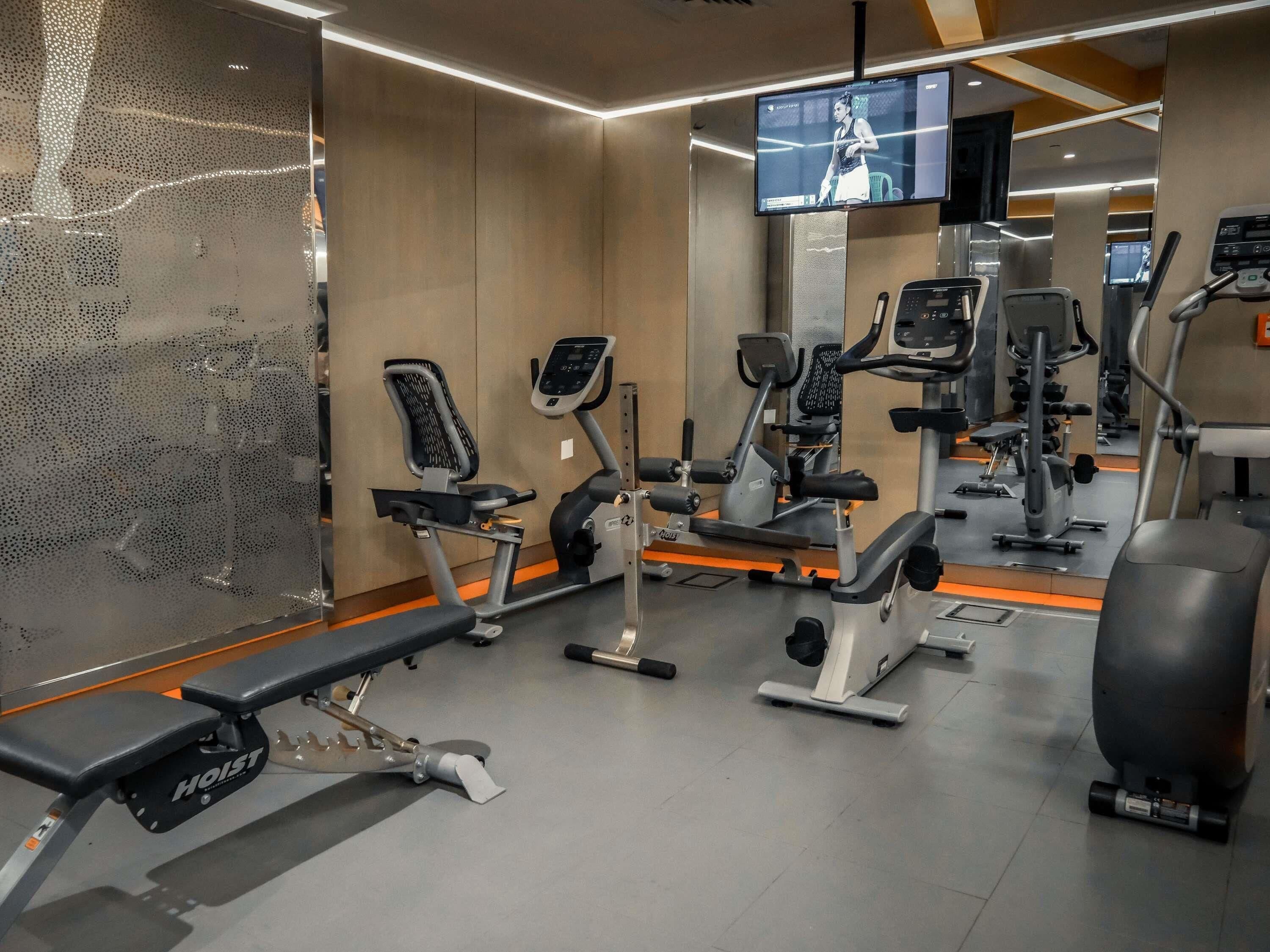 A gym with various exercise equipment, including treadmills, stationary bikes, and weight machines.