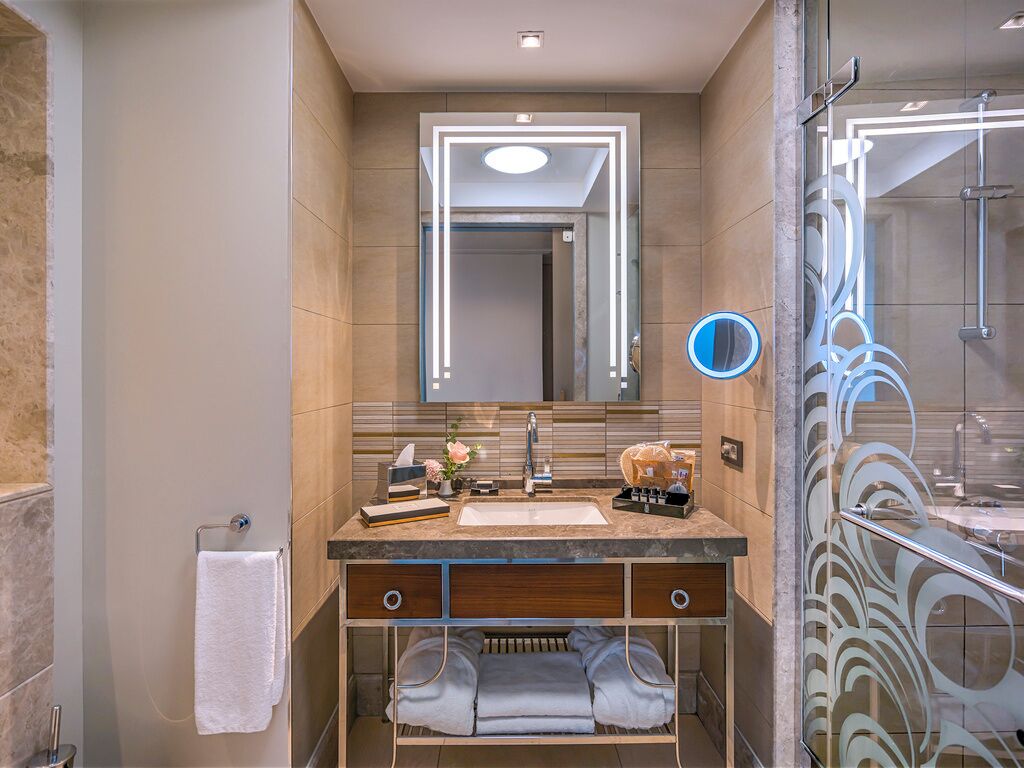 A modern bathroom with a vanity, mirror, towel rack, and shower area.
