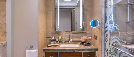 A modern bathroom with a vanity, mirror, towel rack, and shower area.
