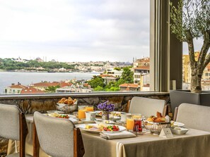 Un desayuno con una mesa para dos, con vistas a una ciudad y un río.