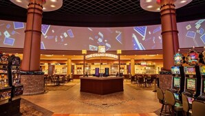 Un hall d’entrée spacieux avec un comptoir central, de nombreux appareils de jeux et un grand écran affichant des images.