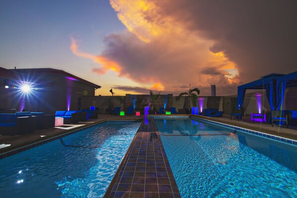 A swimming pool with lounge chairs and a sunset view.
