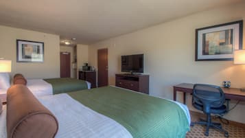 A hotel room with two beds, a desk with a chair, a television, and a framed picture on the wall.