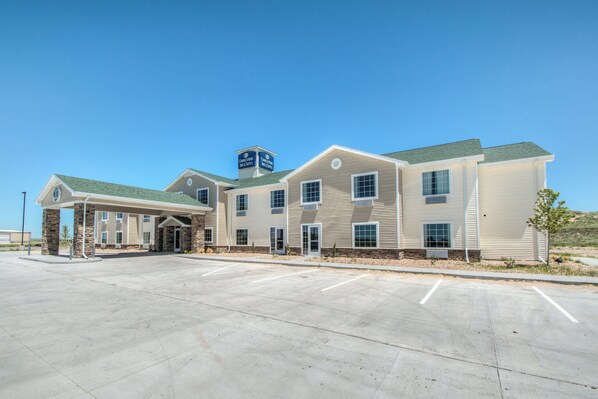 A hotel with a covered entrance, multiple windows, and a parking lot.