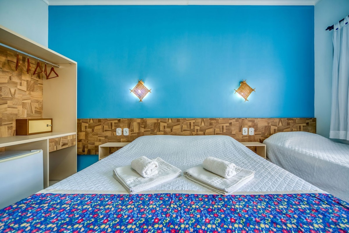 A hotel room with a large bed, two bedside tables, a wooden headboard, and two wall-mounted lights.