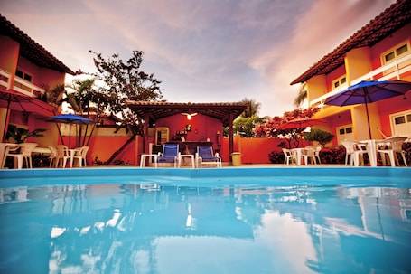 Una piscina al aire libre, sombrillas, sillones reclinables de piscina